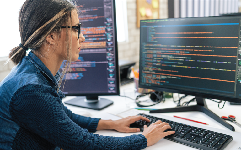 Female software engineer coding and programming on desktop computer