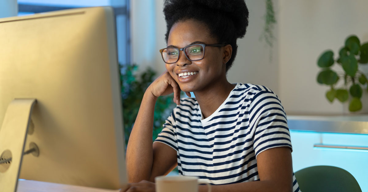 Cheerful millennial woman looking at computer monitor