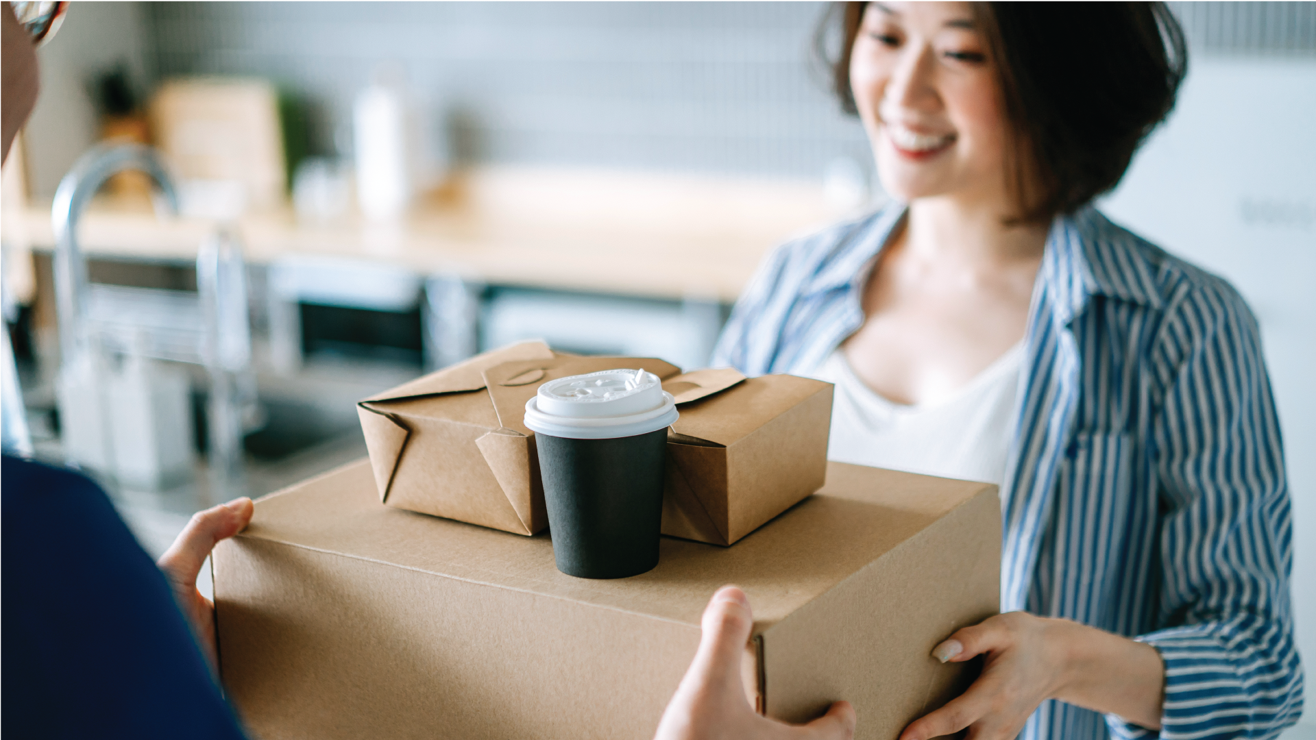 Close up of cheerful young woman receiving delivery takeaway food order from a delivery person